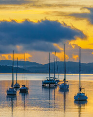 Aerial sunrise waterscape with boats, clouds and fog over the mountain range