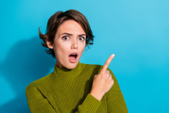 Photo of amazed impressed girl wear trendy khaki clothes arm demonstrate empty space wow news banner isolated on cyan color background