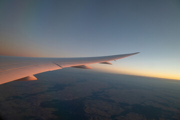 Wing of plane taking off at dawn with beautiful scenery in the background. Concept: Airplanes, holidays, travelling.