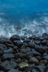 Overhead shot of black rocky beach with blue sea waves. Concept: Beach, volcano, holidays, travelling.