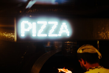 Pizzaiolo putting pizza in the oven