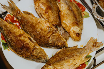 Fried fish in a plate on the table in the kitchen.
