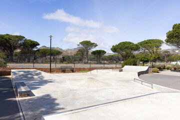 Outdoors, Empty skatepark with ramps and rails on sunny day, ready for skaters