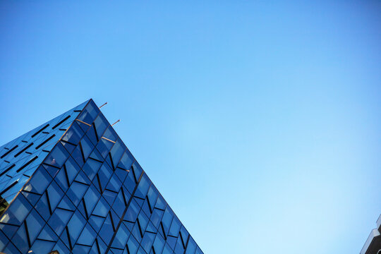 A modern building featuring an intricate geometric glass facade set against a clear blue sky in Wellington, New Zealand