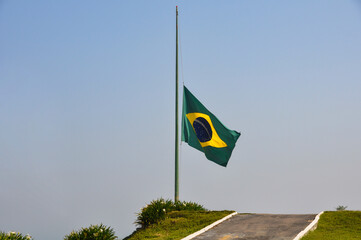 Brazilian flag fluttering in the wind at half-mast in mourning. In the center of the flag with the words “order and progress” in Portuguese. flag day. proclamation of the Republic. proclamation of the