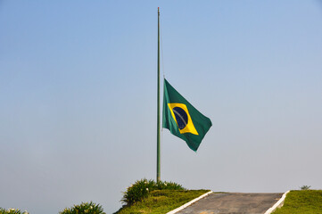 Brazilian flag fluttering in the wind at half-mast in mourning. In the center of the flag with the words “order and progress” in Portuguese. flag day. proclamation of the Republic. proclamation of the