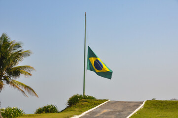 Brazilian flag fluttering in the wind at half-mast in mourning. In the center of the flag with the words “order and progress” in Portuguese. flag day. proclamation of the Republic. proclamation of the
