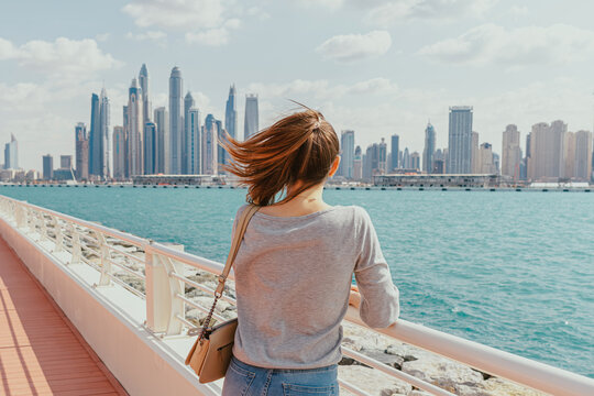 Woman overlooking the city skyline from a waterfront walkway