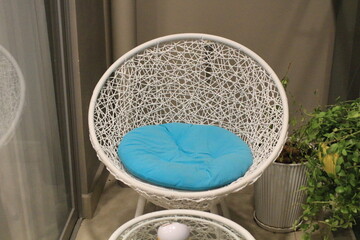 A chair in a cafe with a blue cushion and white cane frame. 