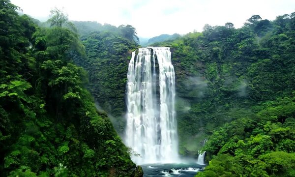 Drone Shot of Waterfall Cascading Down Lush Cliffs