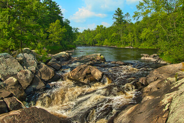 Summer Landscape of the Flambeau River flowing over rocks to form a small waterfall in a pine forest near Loretta, Wisconsin.