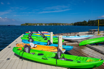 Row of bright colorful kayaks at the dock for rent in Tobermory, Ontario, Canada. Water sports...