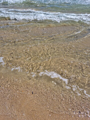 It is a sandy beach with waves rolling in.