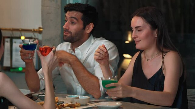Couple or group friends discussing lifestyle and drinking cocktail gin tonic, blue hawaii, Cosmopolitan, Grasshopper at table enjoy engaging conversation celebrating special party nightclub. Vinosity.