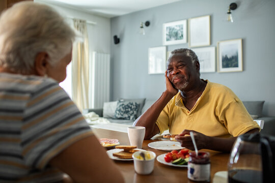 Diverse senior couple eating breakfast together on the kitchen table
