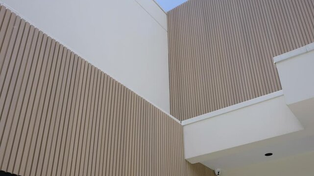 Interior wall with vertical lines creating textured pattern. Ceiling at right angle and another section of building visible in upper left corner which appearing to be balcony