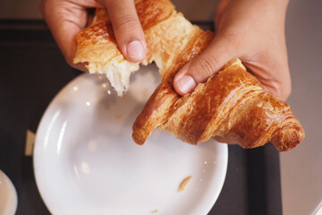 closeup of hand breaking a croissant bun 