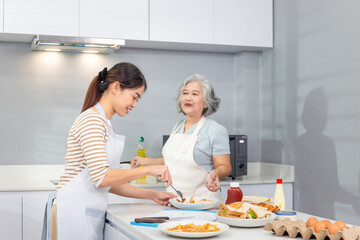 Senior Asian mother and middle aged daughter cooking together at kitchen
