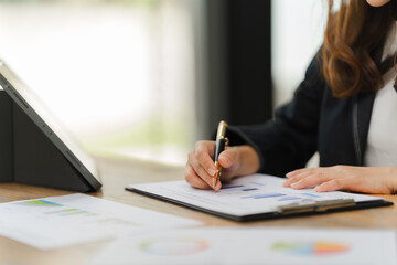 Focused on Success: A professional businesswoman diligently analyzes data on a clipboard, her hand poised with a pen, showcasing dedication and meticulous planning.  