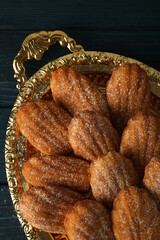 Madeleine cakes on golden platter on blue wooden background, top view