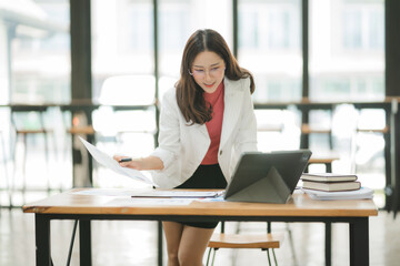 Focused and Determined: A professional woman in a white blazer leans over a table, meticulously...