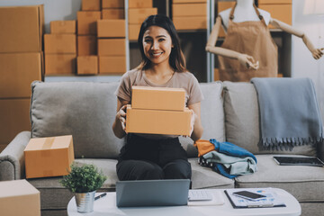 Asian SME business women use laptop computer checking customer order online shipping boxes at home....
