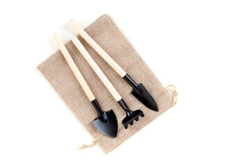 Toy gardening tools on a canvas cinch bag isolated over white