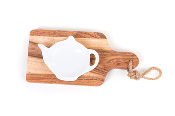 White glass teapot shaped dish on a small wooden cutting board