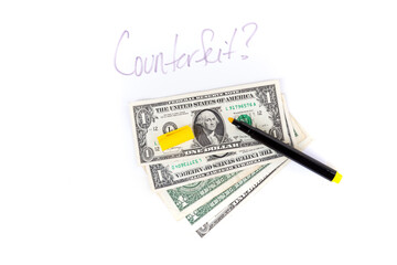 Dollar bills with a counterfeit money check marker
