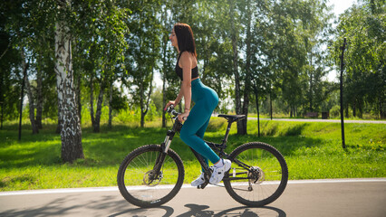 Caucasian woman riding a bike in a park. Vertical photo. 