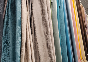 A vibrant collection of textured fabrics hanging in a textile shop showcasing various colors and...