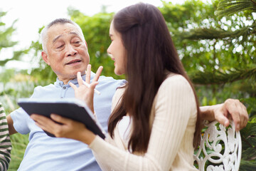 Multi generation Asian family relaxing in backyard garden together.