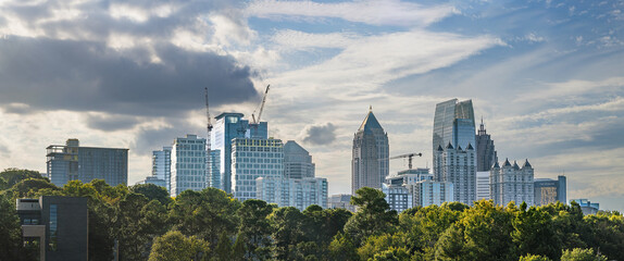 Midtown Atlanta Skyline cityscape showing several prominent buildings and hotels under a blue sky with clouds and sun rays.