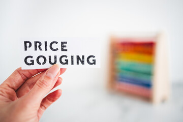 hand holding Price Gouging sign in front of colorful abacus, Inflation and recession concept