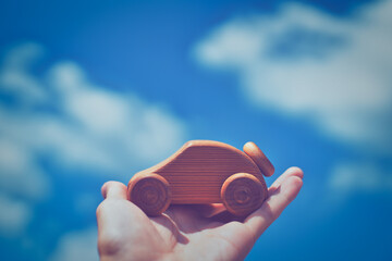 木製の車を持つ人の手と青空背景