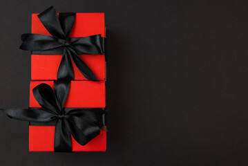Top view photo of red gift boxes with black bow on isolated black background with copy space.