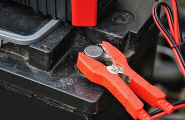 charger clamp on battery terminal close up. selective focus. charging old car battery