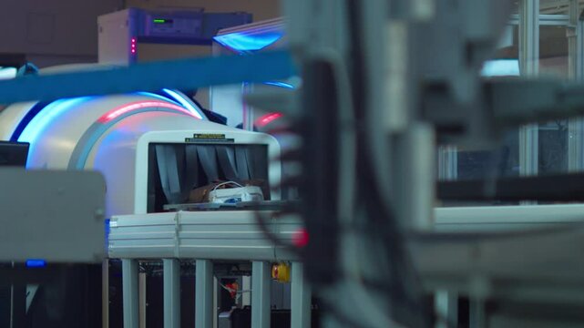 Luggage exiting an X-ray TSA security scanner at an airport and empty bins returned