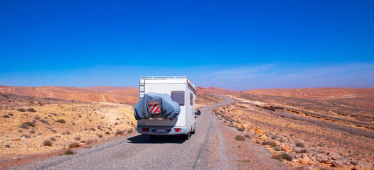 Obraz premium Campervan Alone on a Desert Road in a Scenic Wilderness