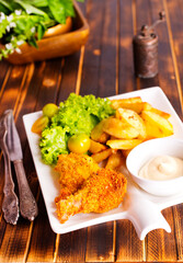 Delicious fried chicken wings accompanied by golden potato wedges served with creamy sauce
