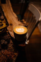 Cappuccino in a ceramic mug on a wooden table with a chair in the background. Delicious quality coffee.