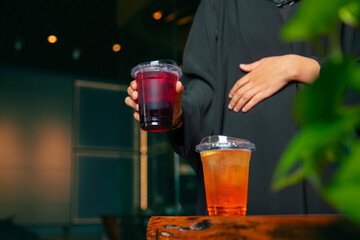 Iced tea in a cafe on the table and being held by a girl