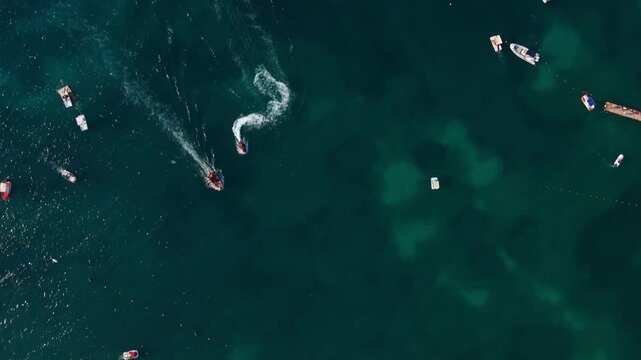 Boats and jet skis create white trails on the blue-green waters of Ksamil, Albania from an aerial view