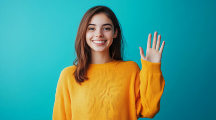 A young woman in a yellow sweater is smiling and waving her hand.