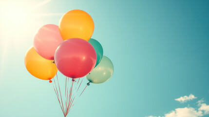 Fototapeta premium A bunch of colorful balloons floating in the sky. The balloons are of different colors, including red, yellow, and green. The scene is bright and cheerful, with the sun shining down on the balloons