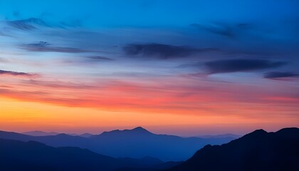 Fototapeta premium The colorful sky with blue and orange hues creates a dramatic backdrop against the silhouetted mountains.