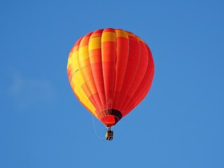 Naklejka premium A vibrant hot air balloon soaring against a clear blue sky, showcasing its colorful design and peaceful flight.