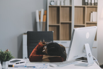 The business lady and the employee take a nap while working on the office desk. Working women are exhausted and sleeping on the table