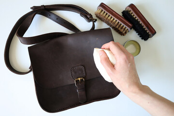 Photo process of cleaning leather products. Crazy horse leather bag. Human hand with a sponge....