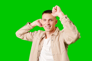 Happy Young Man Celebrating With Raised Arms Against a Green Background
